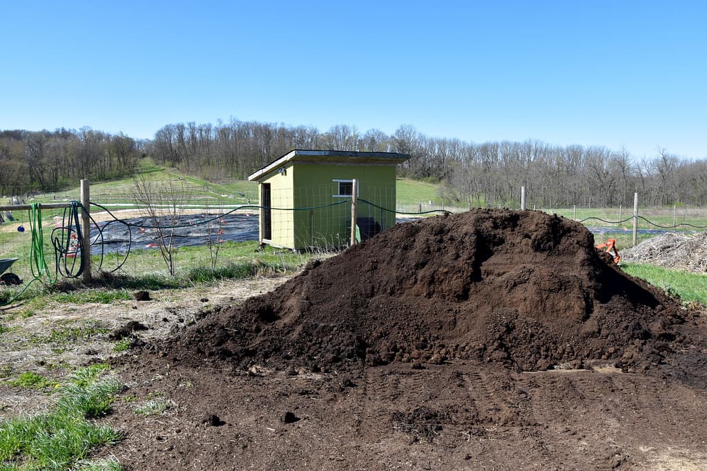 Active compost pile showing layered brown and green material with visible steam